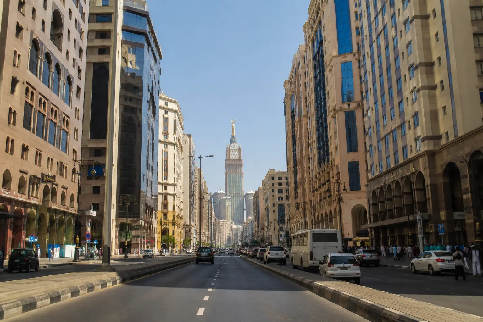 Luxury hotels in Makkah along a wide road leading toward the Abraj Al Bait Clock Tower near Masjid al-Haram.